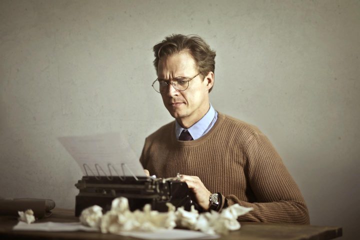 A man typing on a typewriter and repeating the copy many times because of perfectionism